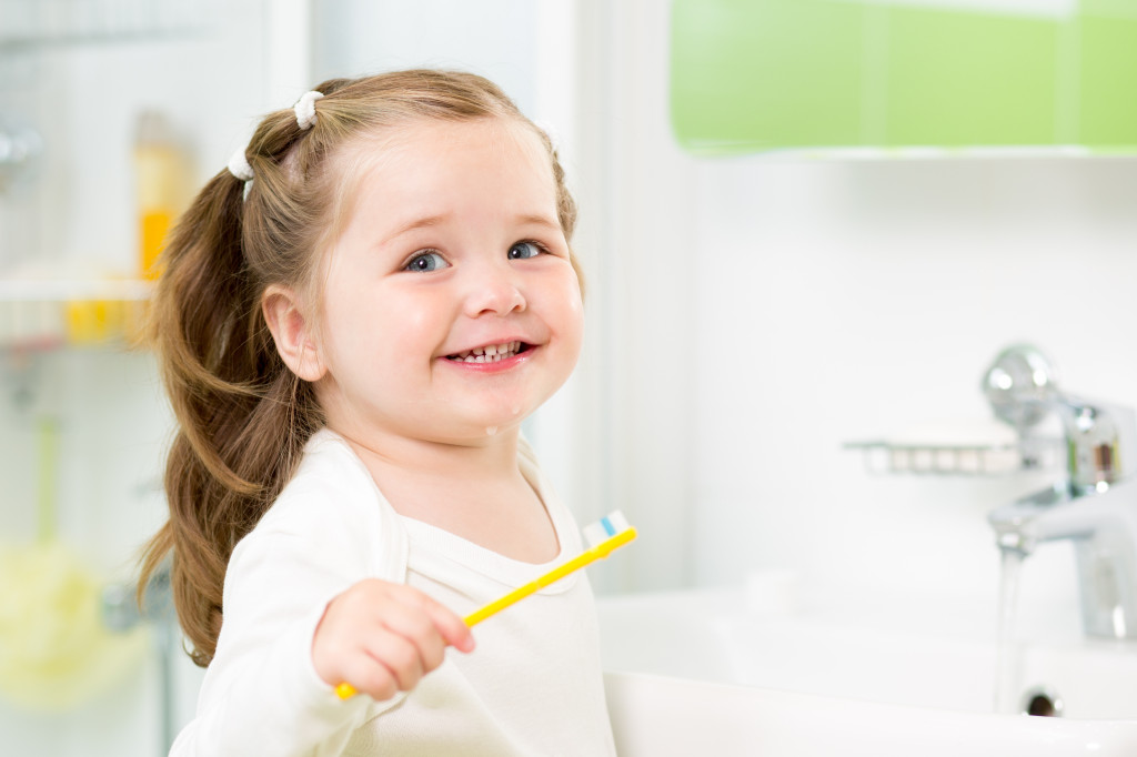 Smiling child girl brushing teeth in bathroom